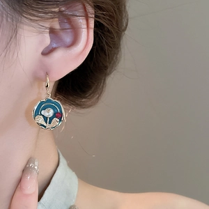Close-up of vintage French earrings with blue enamel flower and gold plating on a model