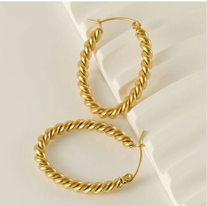 Close-up of golden twisted rope hoop earrings with a matte finish on geometric steps