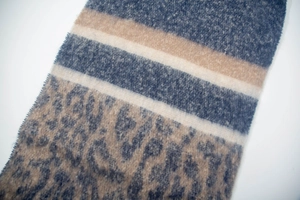 Detail of plush leopard print scarf showing blue animal pattern and striped texture