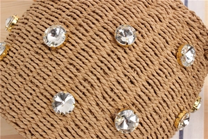 Detail of hand-woven cylinder bag featuring large sparkling rhinestones in gold claw settings
