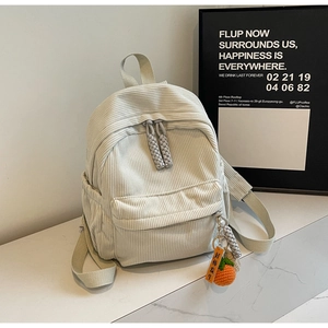 Detailed texture of creamy corduroy small backpack with cute orange knit charm
