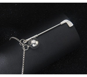 Close-up of silver golf club and ball charms on a metallic link chain necklace