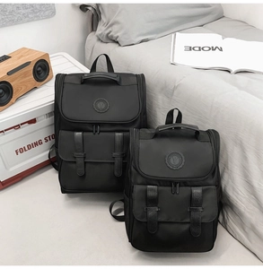 Close-up of two black nylon backpacks with leather buckles in a cozy lifestyle setting