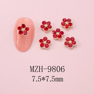 Macro shot of 7.5mm red rhinestone flower nail charms with gold bead center on tips