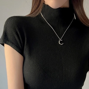 Dettaglio della collana con ciondolo a lettera C argentata su lupetto nero a coste