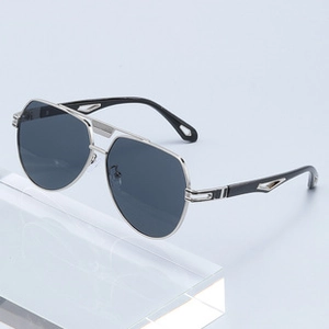 Detail view of silver metal pilot sunglasses with dark grey lenses at a 45-degree angle
