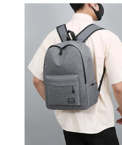 Rear view of model wearing the large heather grey travel backpack with fashion logo