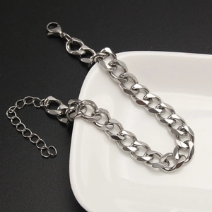Detail of silver Cuban chain bracelet with lobster clasp on white ceramic tray