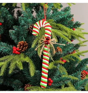 Macro view of red and white striped Christmas candy cane ornament with bells and bow