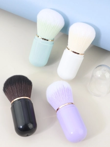 Detail of four colorful capsule makeup brushes with gold rings and clear dust cover