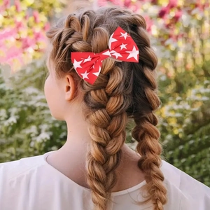 Close-up of American flag bow hair clip with white stars on a braided ponytail
