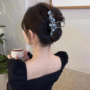 Gros plan sur la pince à cheveux camélia bleu élégante avec strass portée par un modèle
