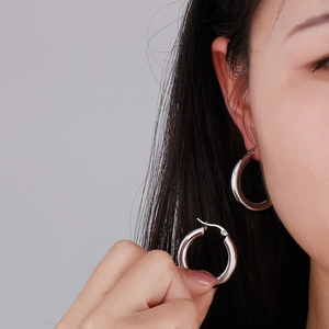Minimalist silver titanium steel hoop earrings for women shown on model and hand