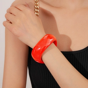 Close-up of chunky red resin wave bracelet worn over black knit sleeve style