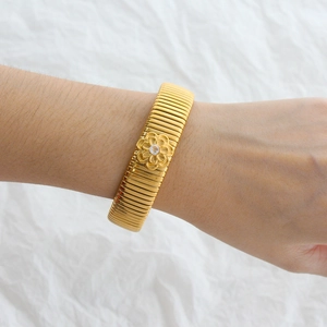 Detail of 18K gold-plated cuff bracelet featuring a central daisy flower and cubic zirconia