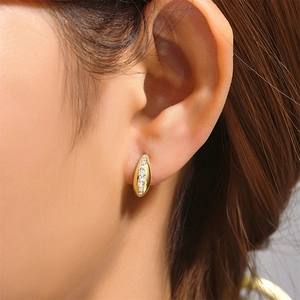 Detail of C-shaped gold stud earring featuring micro-pave cubic zirconia on model