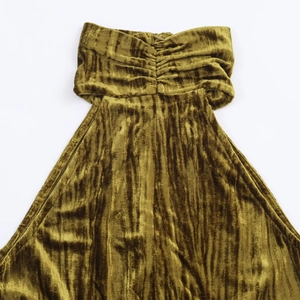 Dettaglio del tessuto in velluto verde oliva con elegante texture a pieghe sull'abito