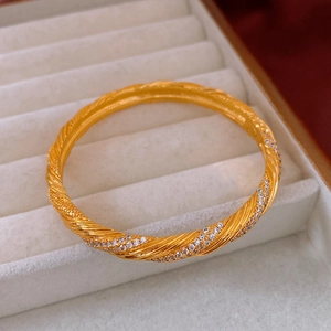 Close-up of vintage twisted gold bangle with micro-pave zircons and textured details