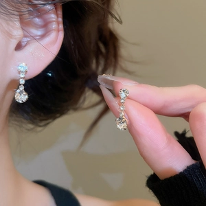 Close-up of silver rhinestone earrings worn by model showing elegant dangling detail