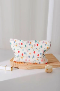 Dettaglio della borsa trucco in tela a pois colorati con etichetta H&R BAG su vassoio
