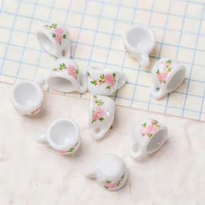 Detailed view of 1:12 scale white ceramic dollhouse tea cups with pink cherry blossoms