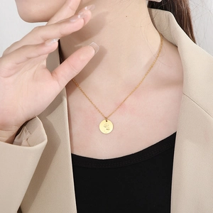 Gros plan d'un collier pendentif rose dorée porté par un mannequin en tenue professionnelle