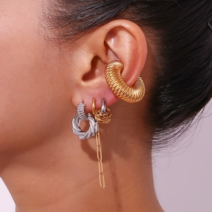 Detailed close-up of mixed gold and silver twisted C-shaped earrings and chain cuff on ear