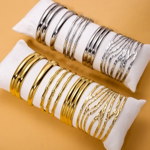 Minimalist vintage gold and silver titanium steel bangles on display pillows