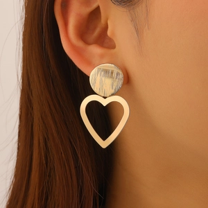 Detailed shot of golden hollow heart earrings featuring a brushed metal round connector