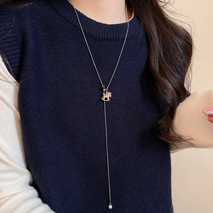 Detail of a tiger eye wood horse pendant with a white pearl on a long rose gold chain