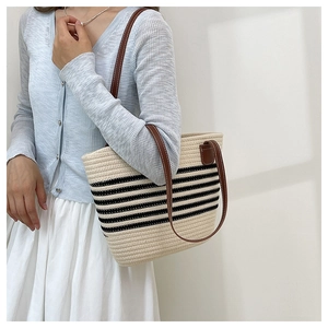 Dettaglio della borsa tote tessuta a righe con tracolle in pelle marrone su modella