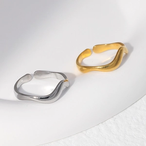 Macro detail of wave-shaped open rings in gold and silver minimalist steel finish