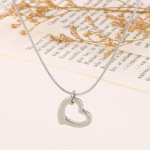 Detailed view of silver heart pendant necklace on a sleek snake chain over floral props