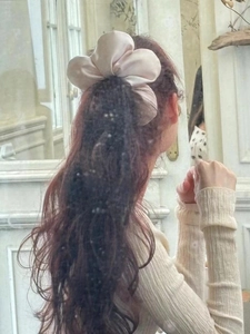 Close-up of fluffy beige satin scrunchie worn on hair showing silky soft fabric texture