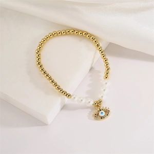 Close-up of golden beaded evil eye bracelet with white pearls and colorful zircons