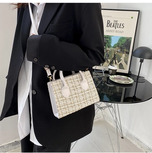 Detail of tweed crossbody bag with gold-tone hardware and white leather handles