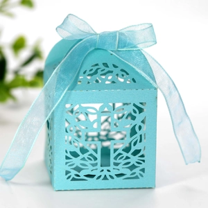 Macro detail of laser-cut cross hollow candy box in light blue with ribbon bow