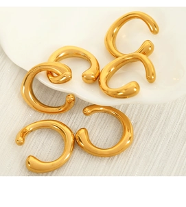 Detail view of five gold C-shaped non-pierced ear clips on a white textured fabric surface
