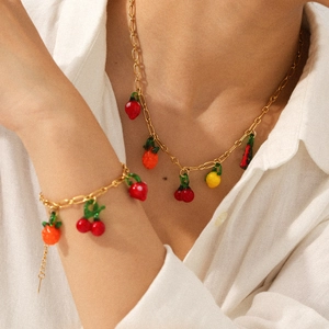 Gold chain necklace and bracelet set featuring colorful glass fruit pendants on a model