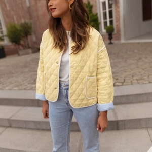 Women's light yellow quilted jacket with crew neck and white piping detail