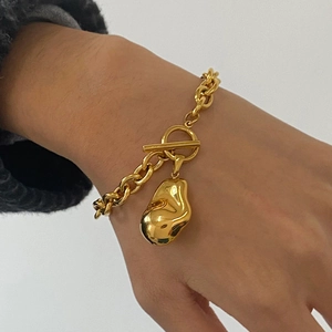 Detail of 18k gold plated chunky chain bracelet with T-bar clasp and curved pendant