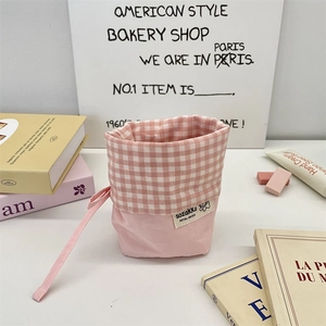 Detailed close-up of pink checkered canvas drawstring stationery bag with fabric brand label