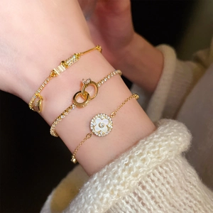 Detailed view of layered gold-plated bracelets featuring zircon and mother-of-pearl accents