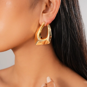Close-up of 18K gold plated irregular geometric hoop earring worn by a model