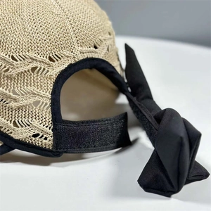Detail view of the beige straw sun hat with adjustable velcro strap and black bow decoration