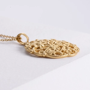 Macro side view of 18K gold plated stainless steel hollow pattern pendant necklace