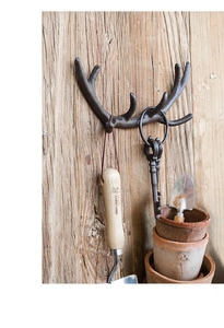 Rustikaler Wandhaken aus Gusseisen in Geweihform auf Holz für Schlüssel und Mäntel