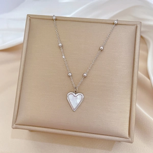 Close-up of heart-shaped white mother of pearl pendant on silver titanium steel chain