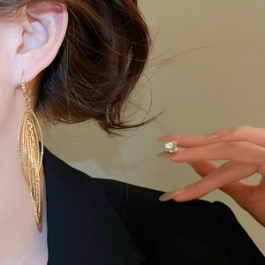 Gros plan d'élégantes boucles d'oreilles pendantes en forme de feuille dorée sur un mannequin