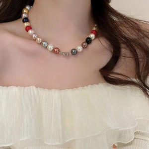 Close-up of colorful pearl necklace with vibrant red, pink and black beads on model